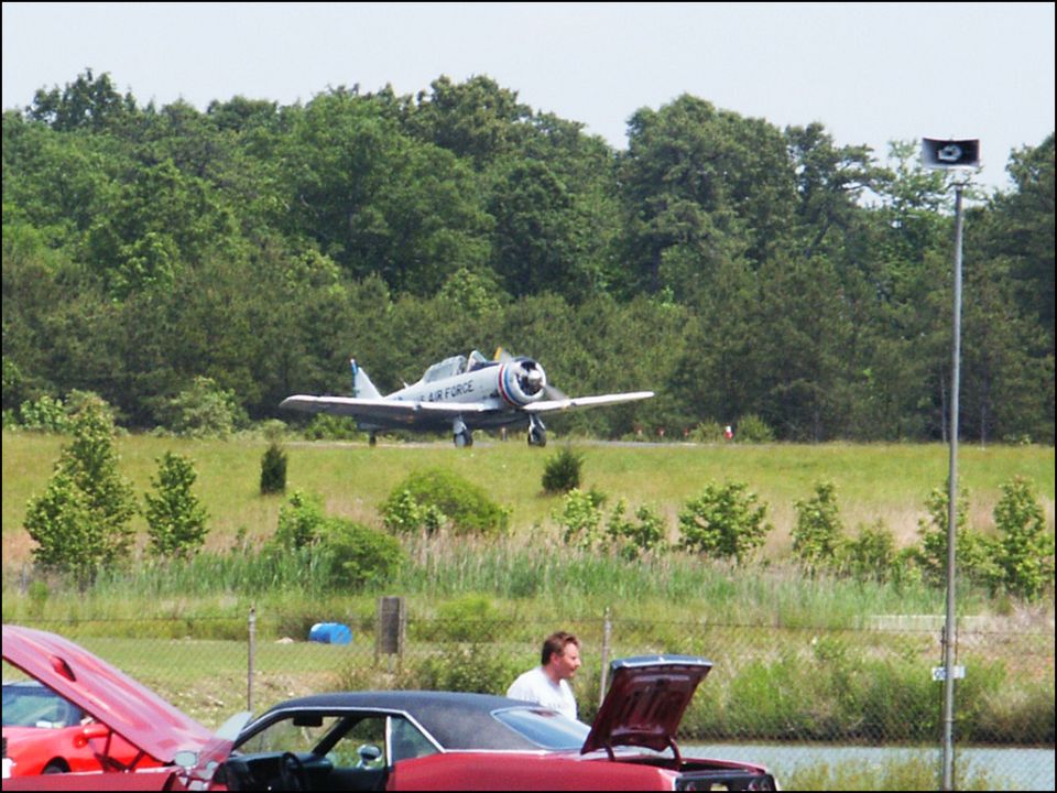 Air Force plane landing near cars with hoods up