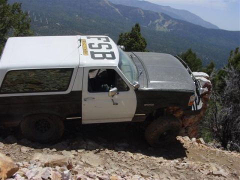 1986 Ford Bronco - Ford Bronco navigates a steep, rocky trail with mountainous scenery in the background.