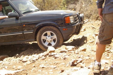 1986 Ford Bronco - A black SUV navigates a challenging rocky terrain on an off-road trail.
