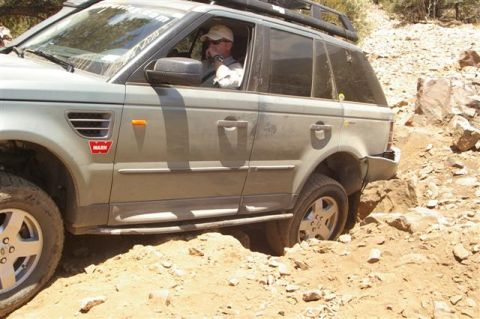 1986 Ford Bronco - SUV with a Warn sticker on the fender is shown off-roading on a rocky, dirt path.