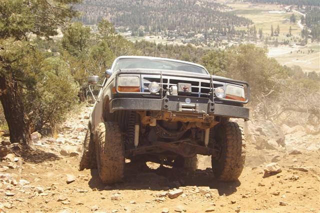Front view of a lifted 1987 Ford F-Series truck on a rocky trail