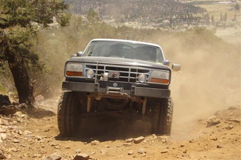 1986 Ford Bronco - Ford Bronco kicks up dust while navigating a steep, rocky trail.