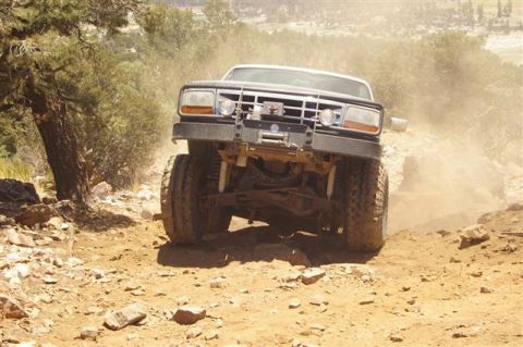 1986 Ford Bronco - A lifted 1987 Ford F-Series truck navigates a dusty, off-road trail with steep inclines.