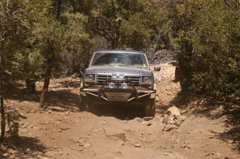 1986 Ford Bronco - This 1986 Ford Bronco navigates a rocky, wooded trail with its distinctive front bumper and auxiliary lights.