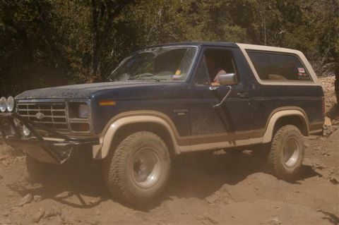 1986 Ford Bronco - Ford Bronco navigates a rocky, off-road path during daylight hours.