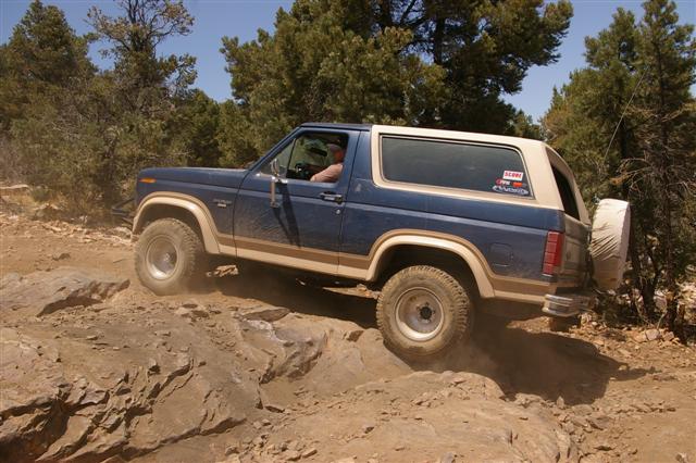 Blue and tan 1986 Ford Bronco navigating rocky terrain