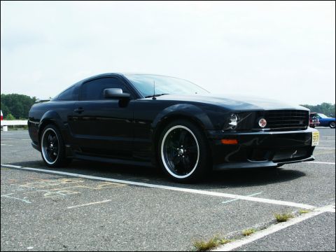 2001 Mercury Grand Marquis - A black coupe with aftermarket wheels is parked on asphalt, with another vehicle visible in the background.