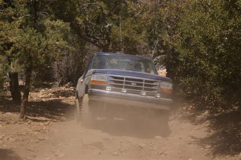 1986 Ford Bronco - Ford Bronco navigates a dusty off-road trail.