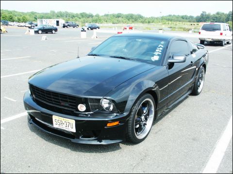 2001 Mercury Grand Marquis - A black Ford Mustang is parked in an outdoor lot, with other vehicles visible in the background.