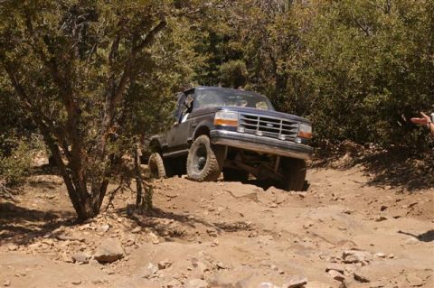 1986 Ford Bronco - This Ford Bronco is navigating a difficult off-road path with steep inclines and loose rocks.
