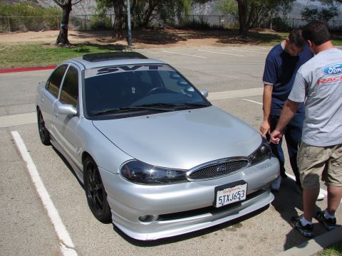 1992 Ford Taurus - Silver sedan with SVT banner and aftermarket wheels parked in a lot.