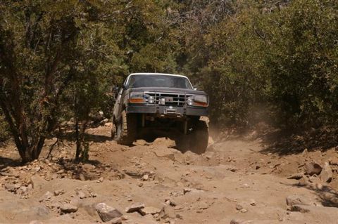 1986 Ford Bronco - This black 1992 Ford Bronco navigates a challenging, rocky off-road path, kicking up dust.