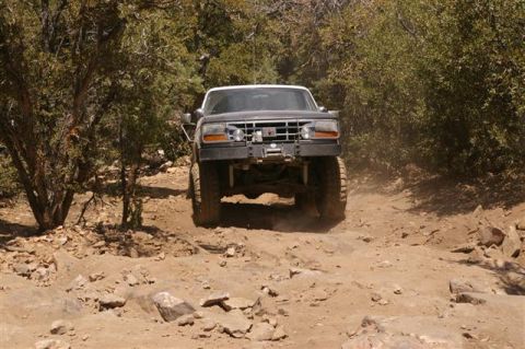 1986 Ford Bronco - This lifted 1992 Ford F-150 navigates a challenging rocky trail, kicking up dust.
