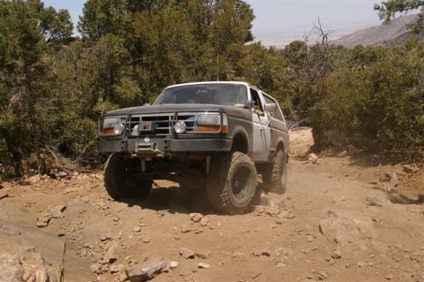 1986 Ford Bronco - Ford Bronco navigates a challenging off-road trail with steep inclines and loose rocks.
