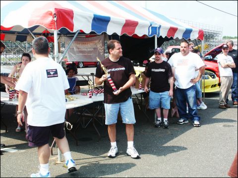 2001 Mercury Grand Marquis - A car show event with attendees, awards, and vehicles present under a striped tent.