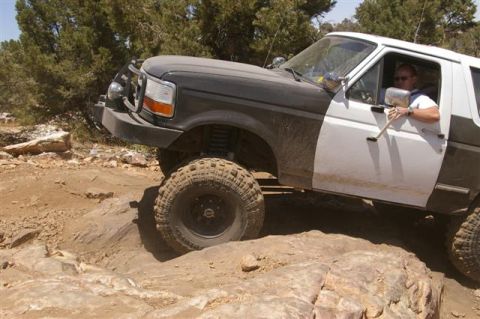 1986 Ford Bronco - This SUV is tackling a challenging rocky trail with large tires and a lifted suspension.