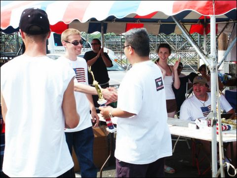 2001 Mercury Grand Marquis - A trophy is presented to a smiling participant at a car and truck show, with other attendees in the background.