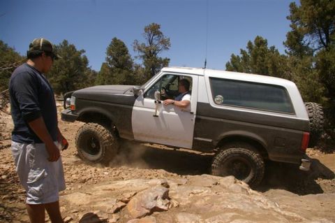 1986 Ford Bronco - A Ford Bronco navigates a challenging, rocky terrain with a driver at the wheel.