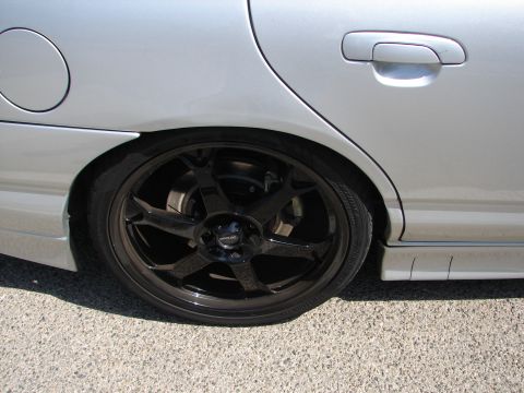 1992 Ford Taurus - Close-up of a silver sedan's rear wheel black aftermarket rims and a lowered stance.
