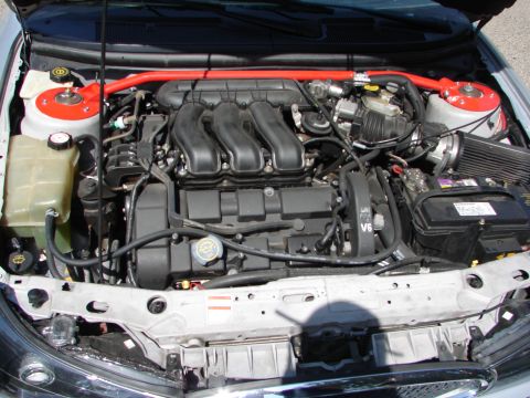 1992 Ford Taurus - The engine bay of a silver car, a V6 engine and a red strut bar.