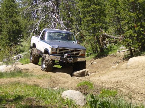 1986 Ford Bronco - This lifted pickup truck navigates a challenging rocky trail, its off-road capabilities.