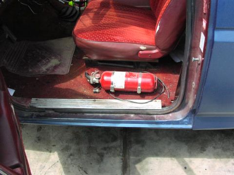 1981 Ford Bronco - The interior of a blue vehicle shows a red fire extinguisher and a red patterned seat.