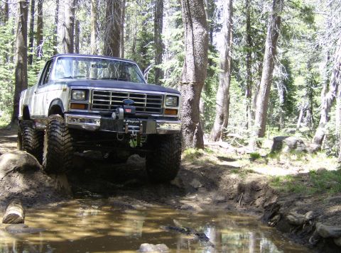 1986 Ford Bronco - This modified Ford Bronco navigates a muddy trail in a wooded area.
