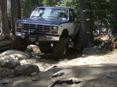 1986 Ford Bronco - This lifted Ford F-Series truck navigates a rocky, wooded trail.