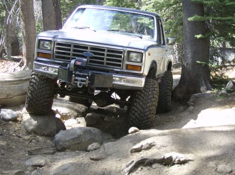 1986 Ford Bronco - Modified 1980 Ford Bronco tackling a challenging off-road trail with large tires and a winch.