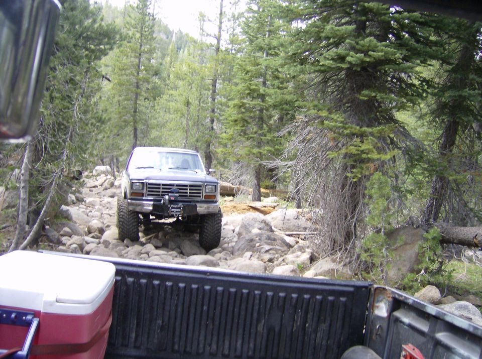 Ford Bronco driving on a rocky, wooded trail. Shot from inside another vehicle