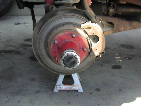 1981 Ford Bronco - Close-up of a vehicle's front wheel hub and brake assembly supported by a jack stand.