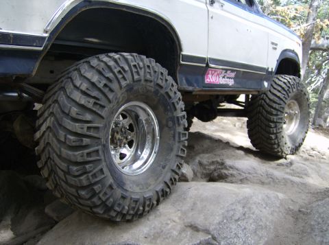 1986 Ford Bronco - This off-road vehicle is navigating a rocky terrain, its large, aggressive tires.