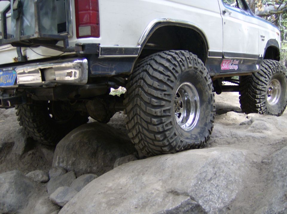 White SUV with oversized tires navigating large rocks