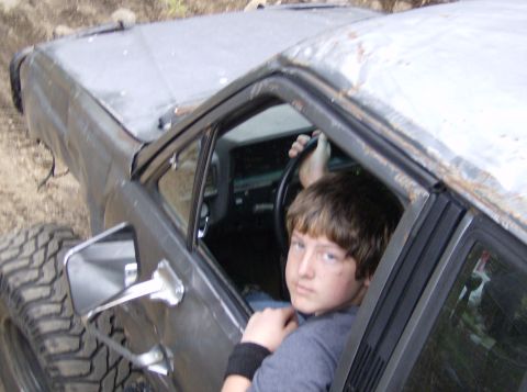 1986 Ford Bronco - A young person sits behind the wheel of a weathered vehicle, ready for an off-road adventure.