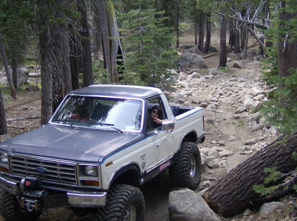 Two-tone gray and white Ford Bronco with large tires on a rocky trail