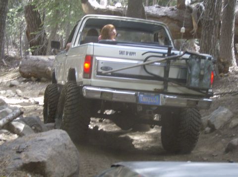 1986 Ford Bronco - This 1986 Ford Bronco navigates a challenging off-road trail with large tires and a spare tire carrier.