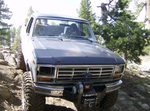 1986 Ford Bronco - This 1986 Ford Bronco navigates a rocky trail, equipped with a winch for off-road challenges.