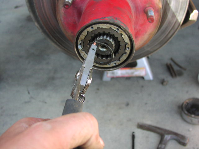 Snap-ring pliers working on a red front hub with splined shaft and retaining ring
