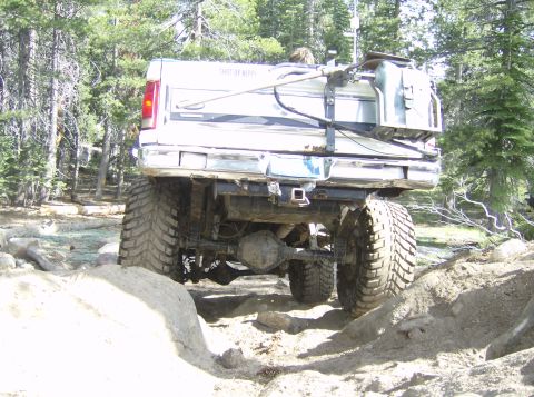 1986 Ford Bronco - This modified pickup truck navigates a challenging off-road course with large tires and a custom fuel tank.