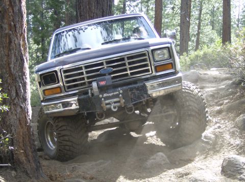 1986 Ford Bronco - A dark gray Ford Bronco navigates a challenging, rocky off-road path.