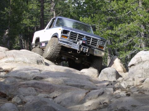 1986 Ford Bronco - This 1980s Ford Bronco is navigating a challenging rocky trail with its front tire high in the air.