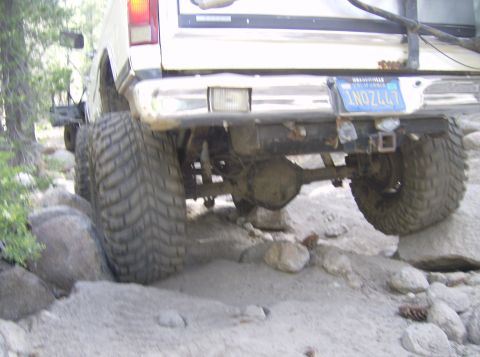 1986 Ford Bronco - This truck is off-roading on a rocky, dirt path with large tires.