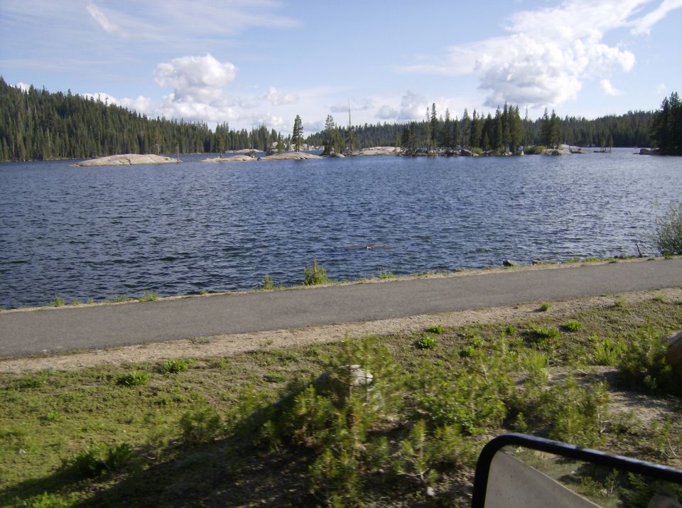 Waterfront scene with a lake, trees, and a paved path
