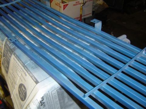 1979 Ford Bronco - Metal grille painted blue, resting on newspapers. Part of a restoration project.