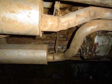 1979 Ford Bronco - The underside of a vehicle shows significant rust on the exhaust system and frame.