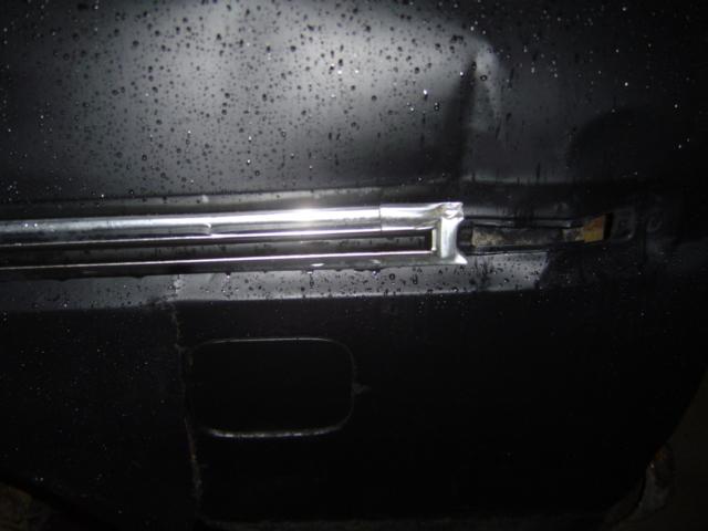 Chrome trim on dented black panel with water droplets