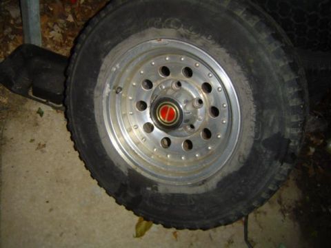 1979 Ford Bronco - A close-up shot focuses on a single vehicle wheel and tire, with visible branding on the tire.