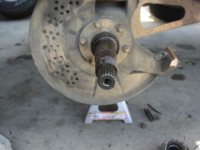 Close-up of splined stub axle and hub with lug studs over a jack stand on concrete