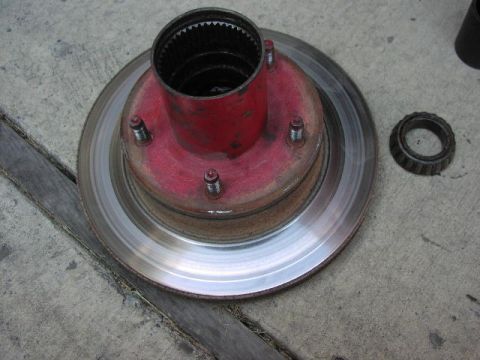 1981 Ford Bronco - A red hub assembly, brake rotor, and bearing are shown on a concrete surface.