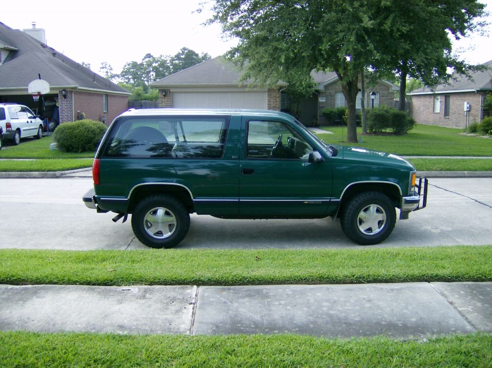 Green two-door SUV parked on a suburban street, side view. Appears to be a 1995 model